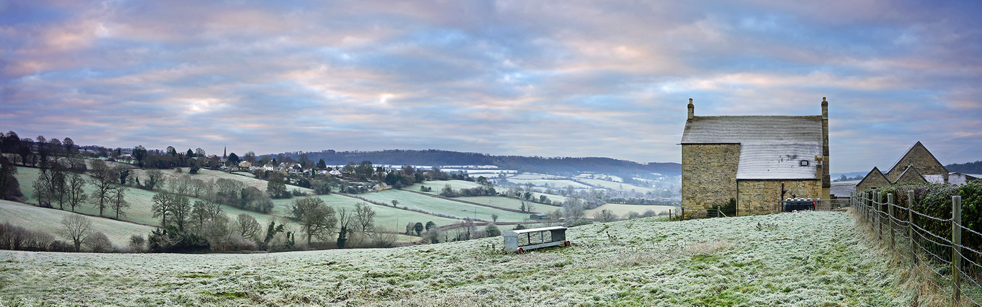 Winter rural cottage in a field with dusting of snow
