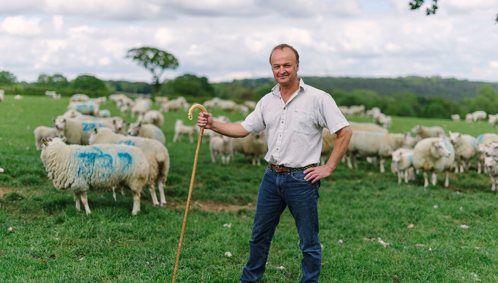 Farming Member Clive Sage Standing Infront Of Flock of Sheep