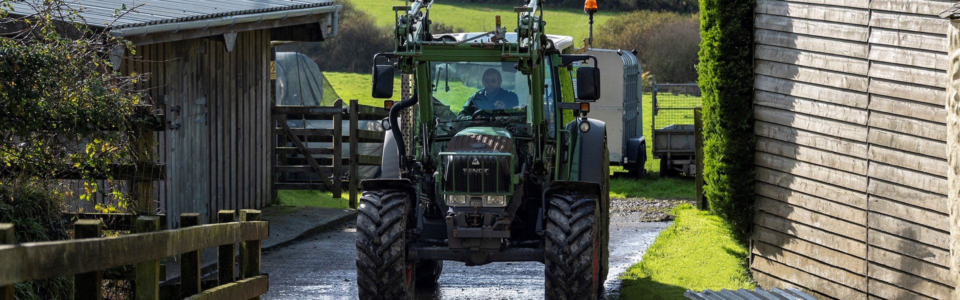 Tractor Driving Down Farm Lane With Farm Background