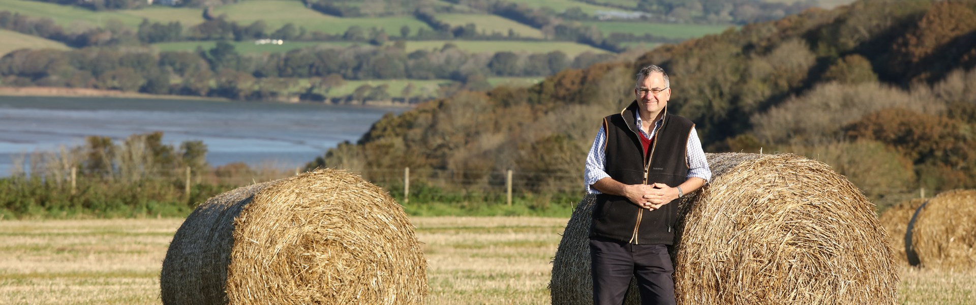 Jeremy Oatey Cornish Mutual Chairman in field leaning against haybale