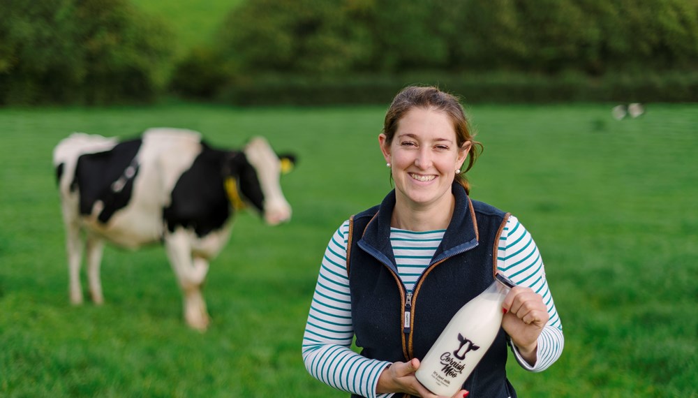 Gemma Smale-Rowland Holding Cornish Moo Milk Bottle with Cow In Background