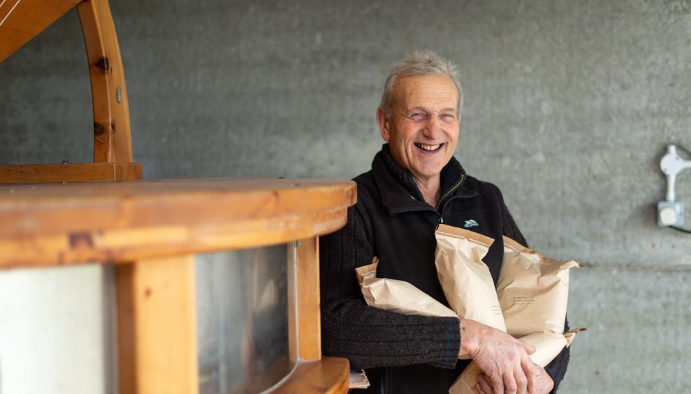 David Buscombe standing next to Cornish Mill and holding bags of flour