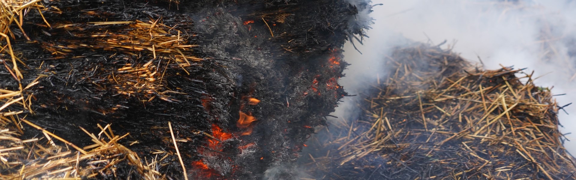 Hay on fire with embers and smoke